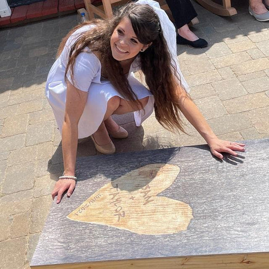 Bride kneeling next to cornhole board