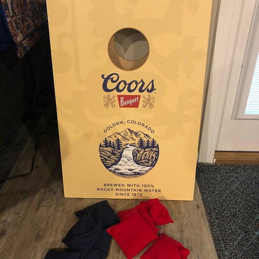 Coors Banquet themed cornhole board with red and blue bean bags.