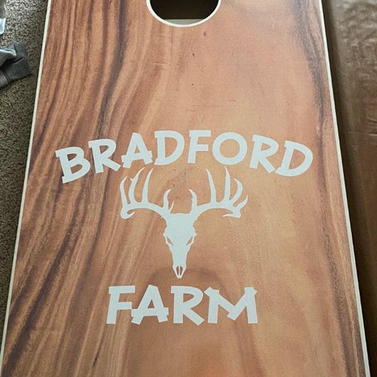 wood grain cornhole board featuring a white deer skull graphic.