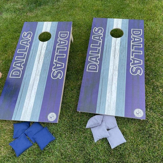 white striped wood grain cornhole boards with blue and grey bean bags on a lawn