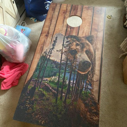 Cornhole board with bear and forest graphic.