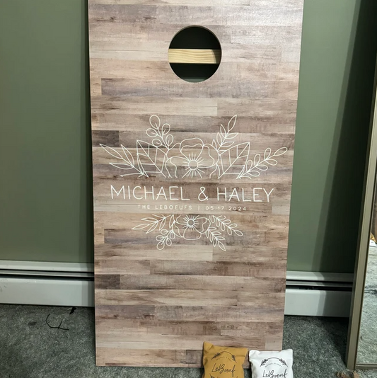 cornhole board with floral line art and a weathered wood plank design