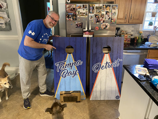 Man with two cornhole boards: one Tampa Bay, one Detroit