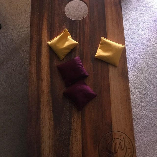 Wooden cornhole board with yellow and maroon beanbags